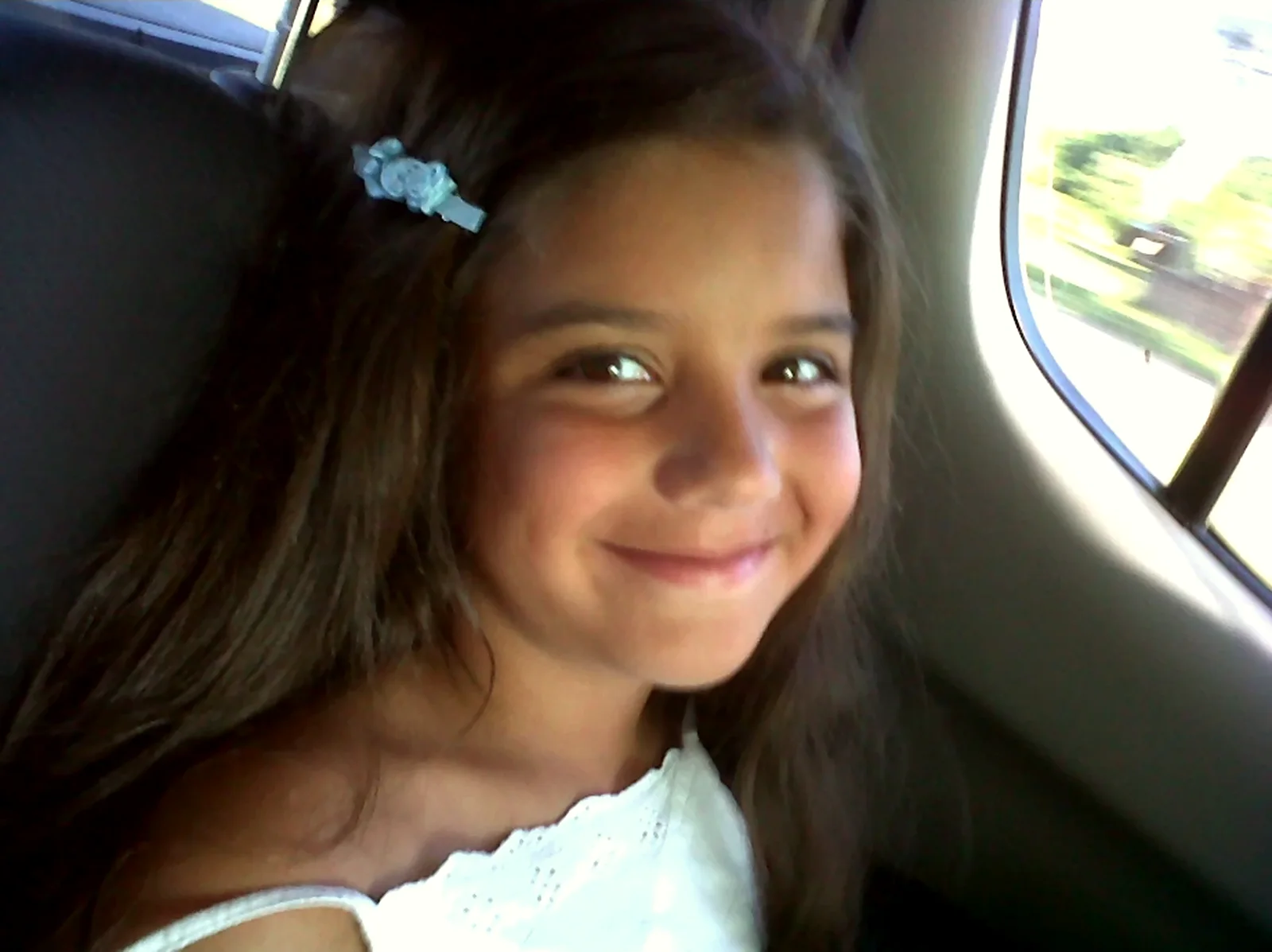 Majo de nena, sonriendo en el asiento de atrás de un auto